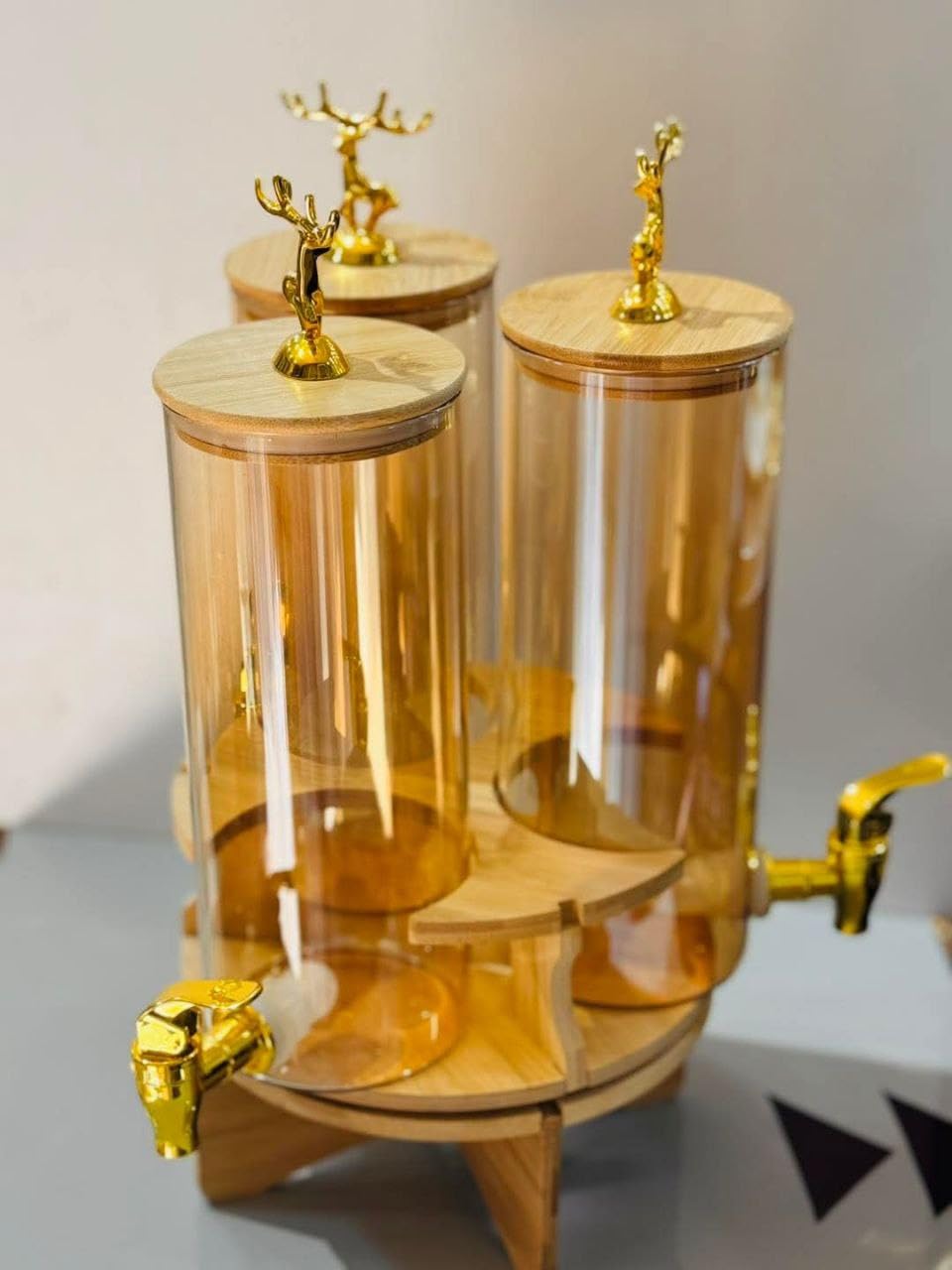 Elegant Triple Section Glass Beverage Dispenser with Gold Deer Lid, Wooden Stand, Round Design, Perfect for Gatherings.